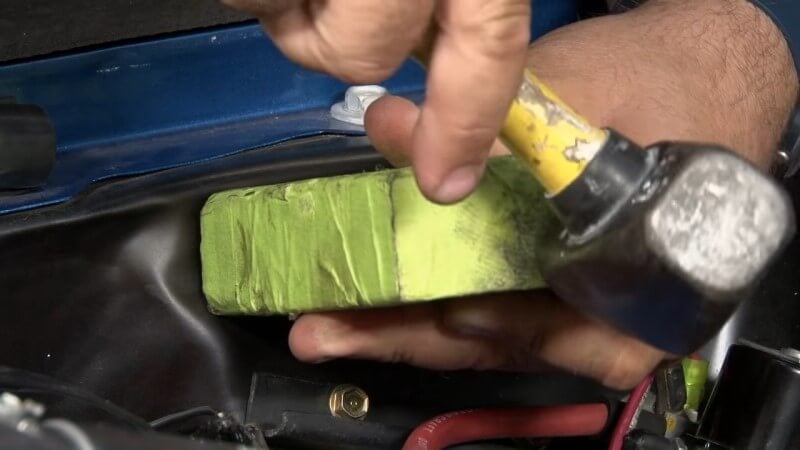 Mechanic hammering down bumps in the engine bay