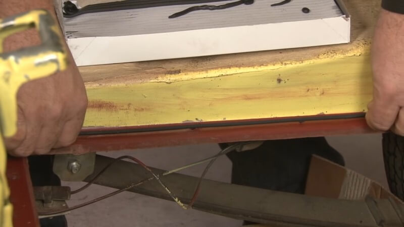 Mechanic applying strip caulk to the trunk area