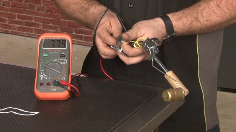 Mechanic testing the new sending unit with a multimeter