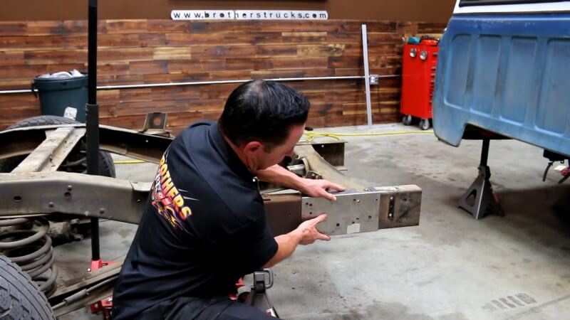 A mechanic sliding the conversion template over the rear frame to line up with the proper holes
