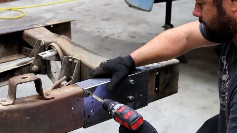A mechanic using a drill to drill through the indicated holes on the conversion template