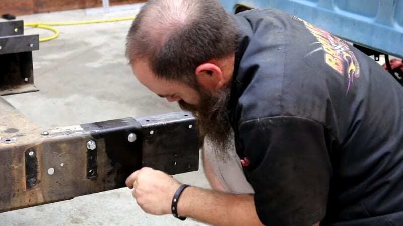 A mechanic hand-tightening the bolts on the C-channels to secure them to ensure they're in the correct position