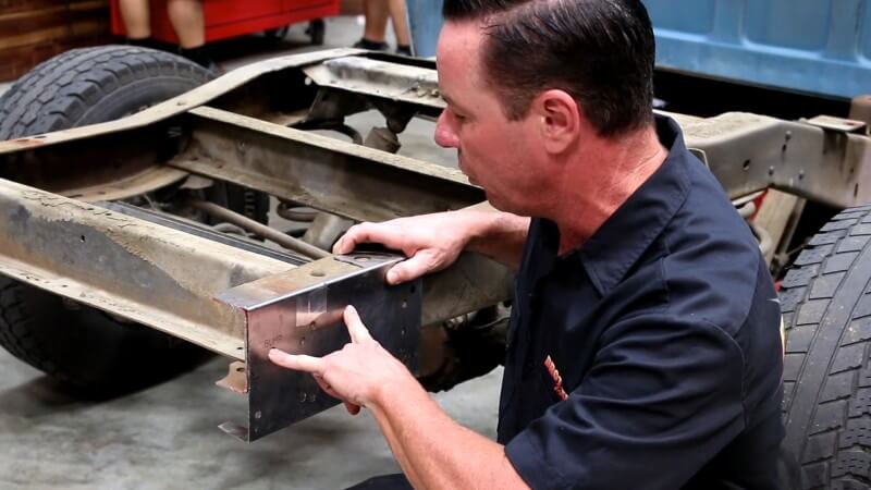 A mechanic pointing at the new bumper mounting holes that need to be drilled out on the template