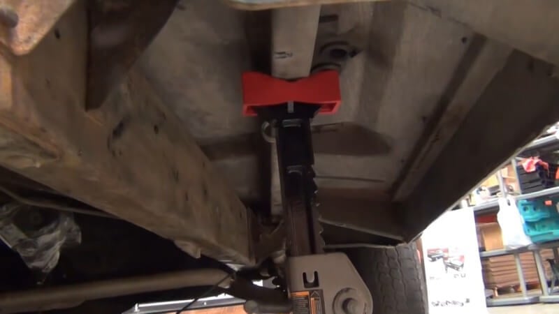 A close up of a set of jack stands set up under the outrigger panels of the truck supporting its weight
