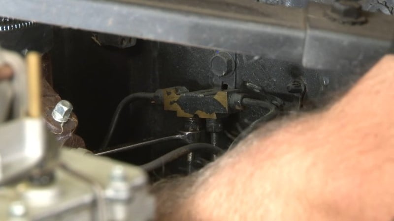 A mechanic loosening the rear brake line with a wrench to remove it from the distribution block