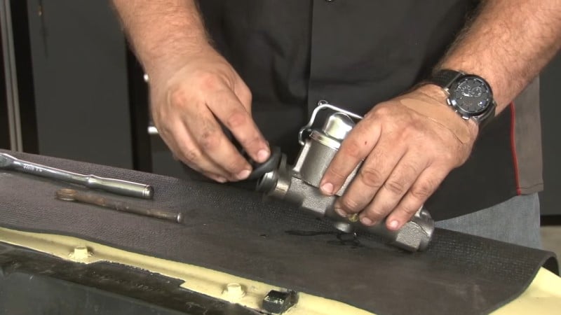 Mechanic sliding the new pushrod boot over the new master cylinder