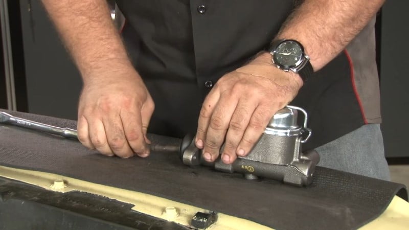 Mechanic pushing the factory pushrod into the new master cylinder