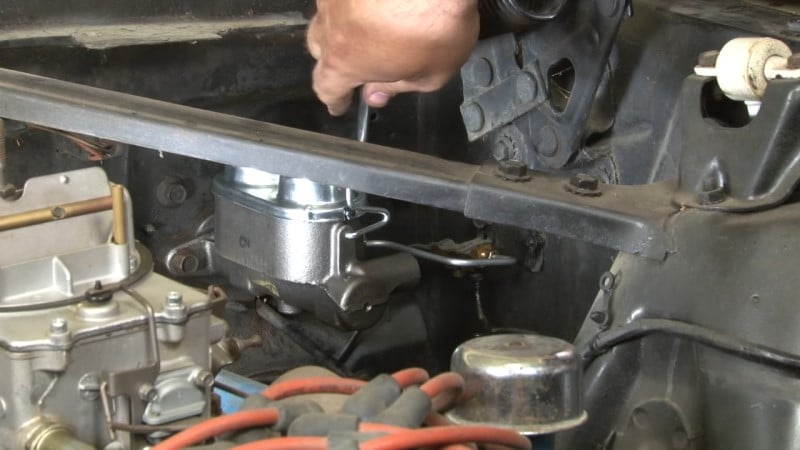 Mechanic tightening the new front brake line to the master cylinder with a wrench
