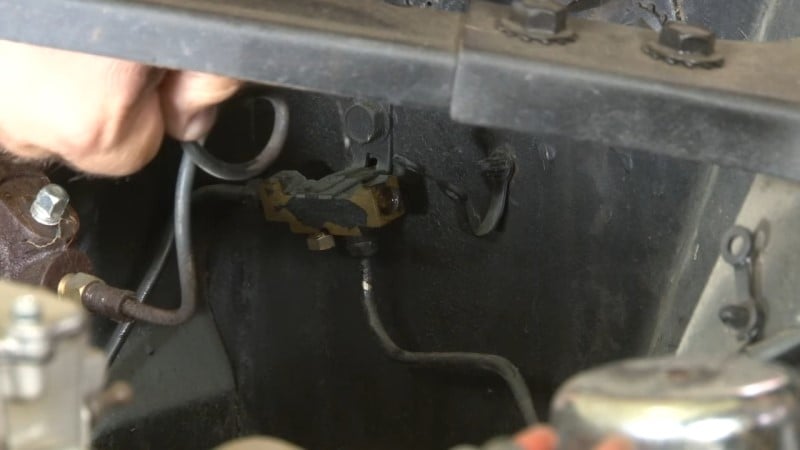 Mechanic moving the front brake line out of the way after disconnecting it from the distribution block