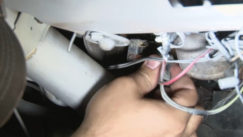 Mechanic disconnecting the brake light switch harness underneath the dash