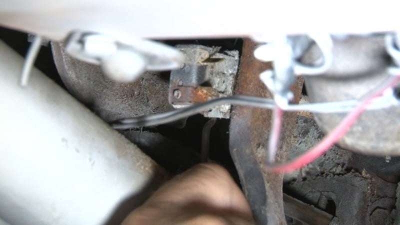 Mechanic removing the cotter pin holding the pushrod to the brake pedal with a hook