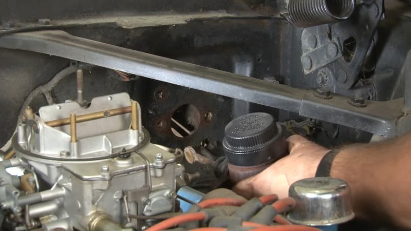 Mechanic pulling the factory master cylinder out of the engine bay