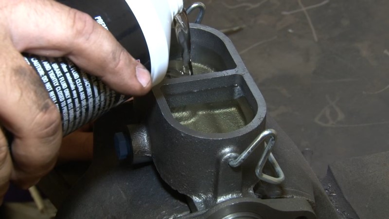 Mechanic pouring brake fluid into the top reservoir until it's full