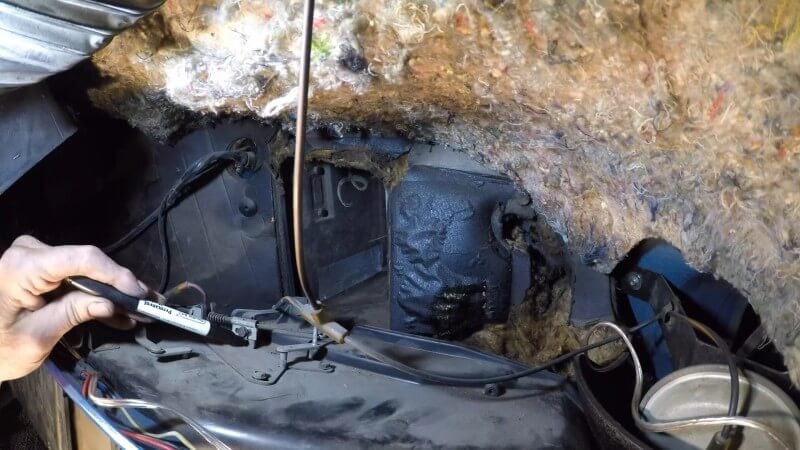 A close up of a mechanic using a black marker to mark the positions of the heater control cables before removing them