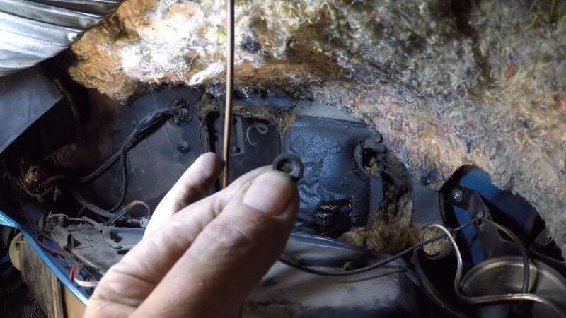 A mechanic holding the small control cable retaining clip up to the camera after removal