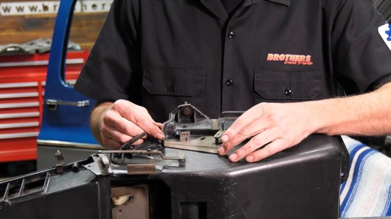 A close up of a mechanic centering the control cable bracket on the side of the heater core box