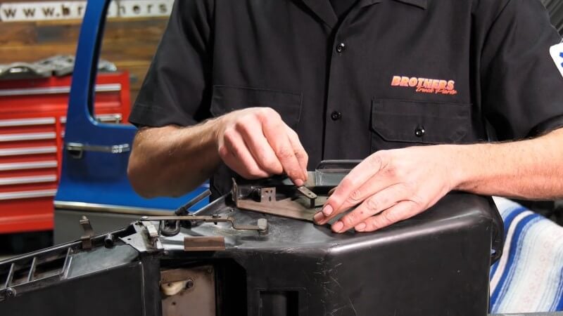 A mechanic using his fingers to open and close the heater control door to ensure proper movement