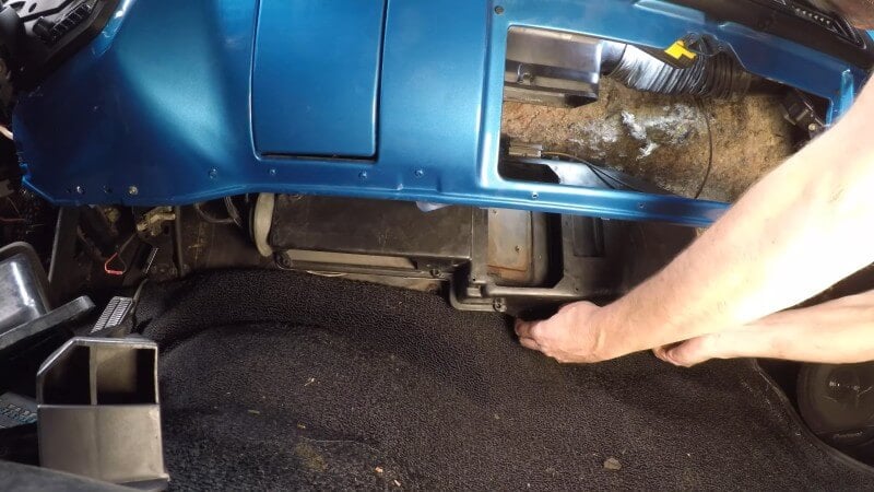 A close up of a mechanic hand tightening the heater box mounting nuts