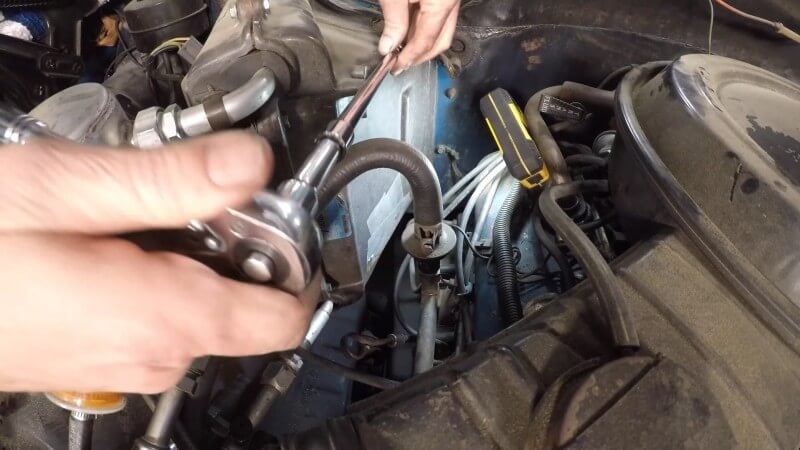 A mechanic using a socket wrench to remove the remaining heater box nuts