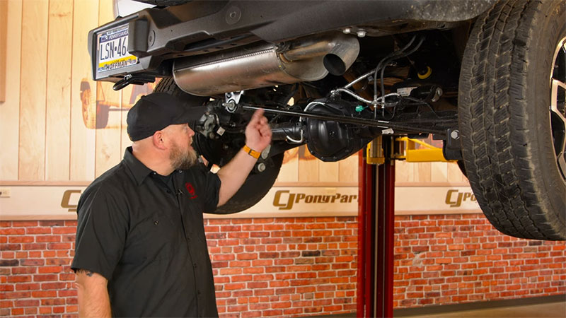 6th Generation Ford Bronco lifted with a mechanic pointing to the muffler