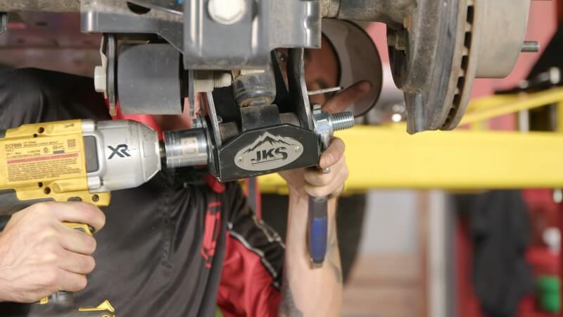 A mechanic tightening the skid plate mounting bolt with an impact wrench