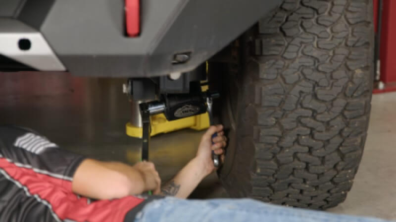 A mechanic using a torque wrench to tighten the skid plate bolts to the required specs