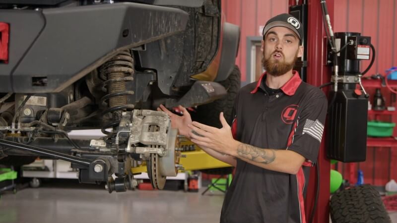 A mechanic pointing at a Ford Bronco with the wheels removed