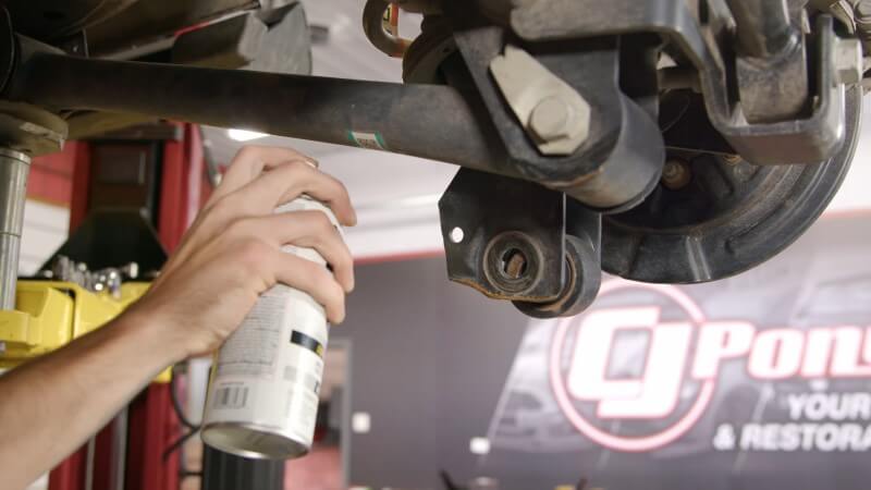 A mechanic spray painting the modified shock bracket to prevent rust