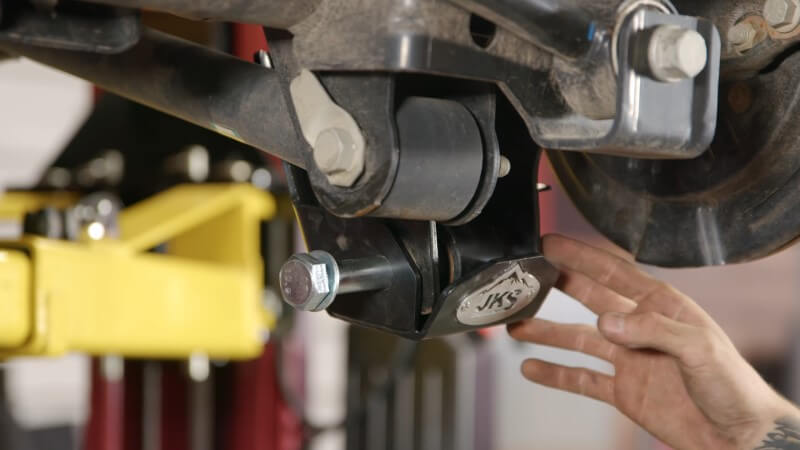 A mechanic pointing at the skid plate mounting bolt after it was installed