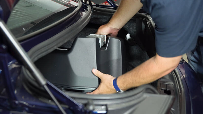 Mechanic unplugging the housing of an S550 Mustang subwoofer
