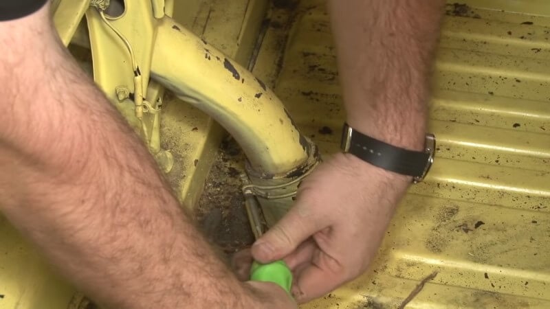 Mechanic loosening the filler pipe clamps