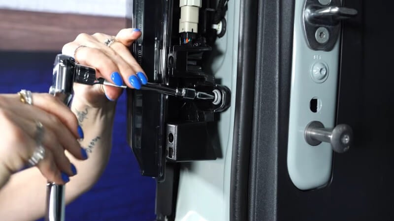 A close up of a mechanic using a ratchet to reinstall the taillight mounting bolts of a white Ford Bronco