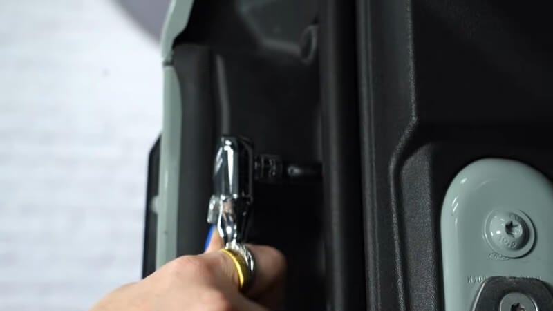 A close up of a mechanic using a ratchet to reinstall the trim panel bolts