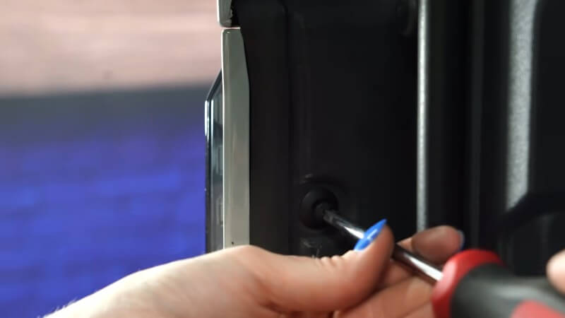 A close up of a mechanic using a screwdriver to tighten the retainer clip screws into place