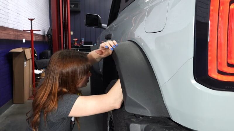 A close up of a mechanic pushing the fender flare into place and locking it down