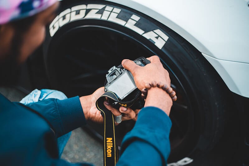 Photographer taking a picture of a car's wheel