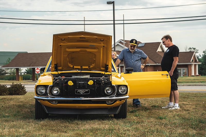 Two men talking next to a Classic Mustang