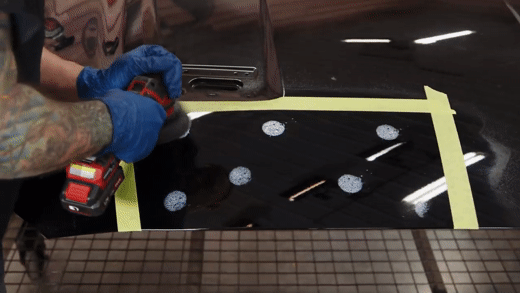 Polishing a black Mustang hood with a mechanical polisher