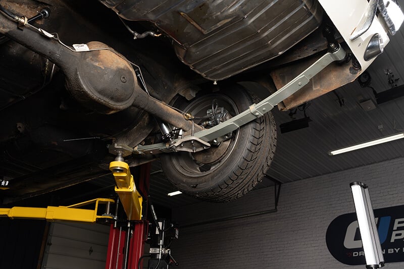 A wide angle shot of the undercarriage of a classic Mustang, specifically showcasing the rear suspension