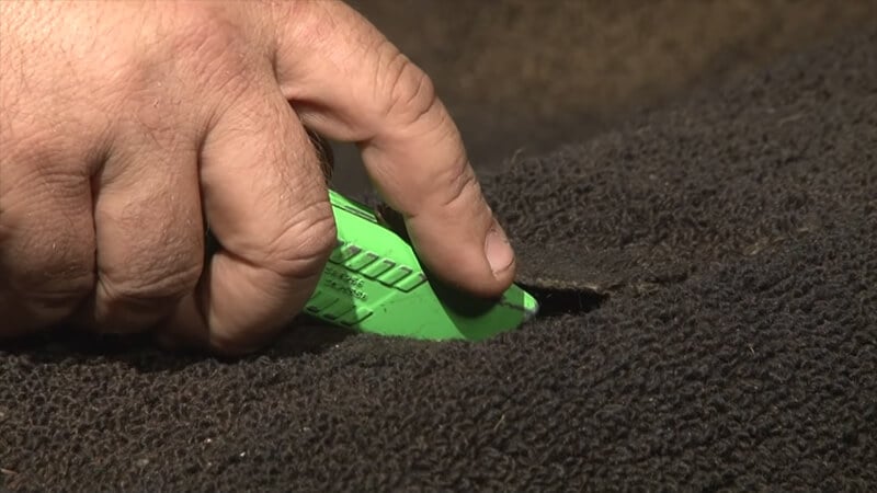 Bill uses a box cutter to cut through the old carpet into the new carpet so they’ll line up