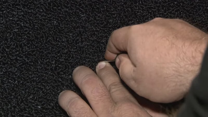 Bill uses an awl to punch a hole in the carpet