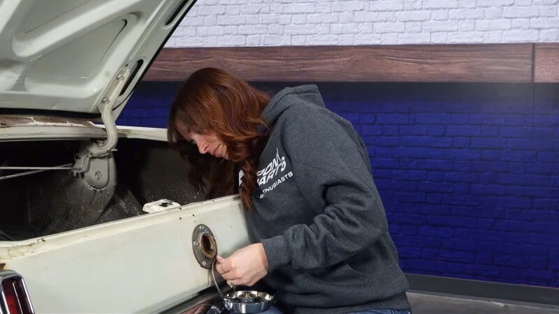 A female mechanic screwing the new retaining nut into place on the back of the new gas cap