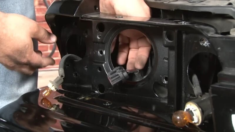 A mechanic feeding the wiring harness through the holes in the frame for the new lights
