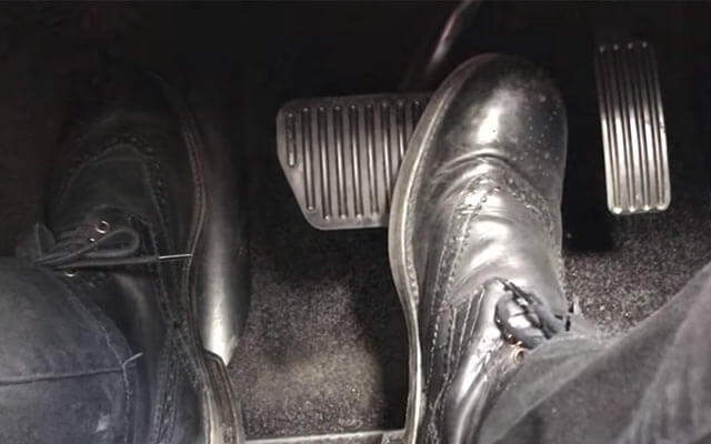 A foot hovering over brake and gas pedals