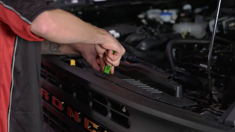 Mechanic removing the front trim panel on a 2021 Ford Bronco