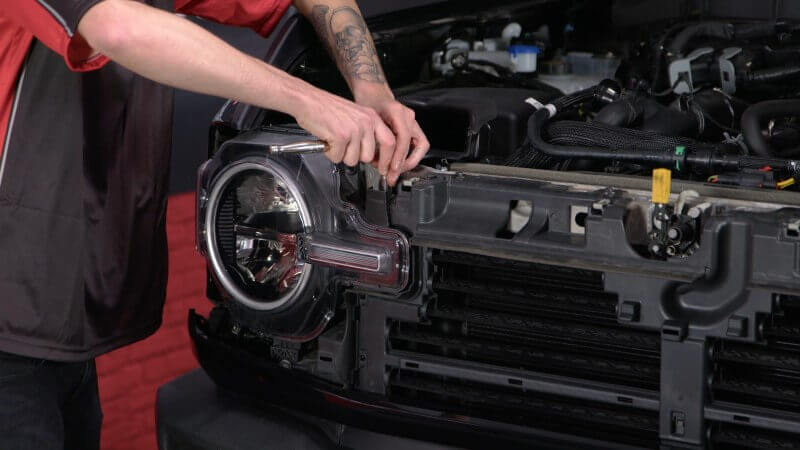 Mechanic removing the stock headlights on a 2021 Ford Bronco