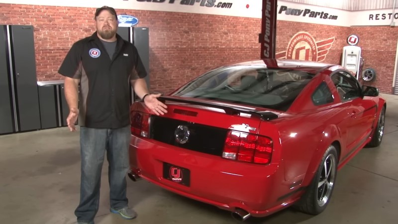 Mechanic Standing In Front Of a Red Mustang In a Garage
