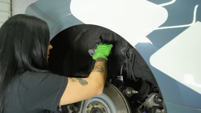 A mechanic pulling the rear shock out of a 2024 Mustang GT