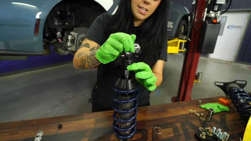 A mechanic seating the coil spring and pushing the bushing down into place