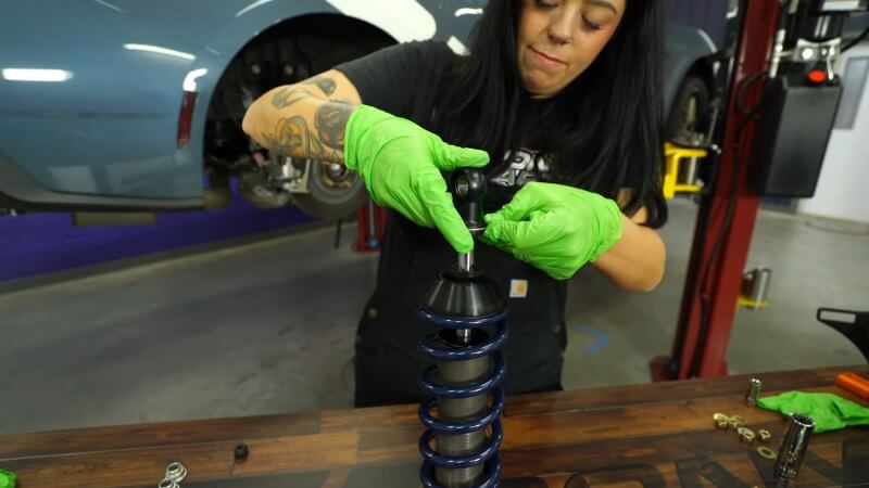 A mechanic sliding a silver metal ring into place on the top of the shock